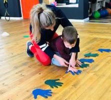 Instructor helping child align hand onto hand print.